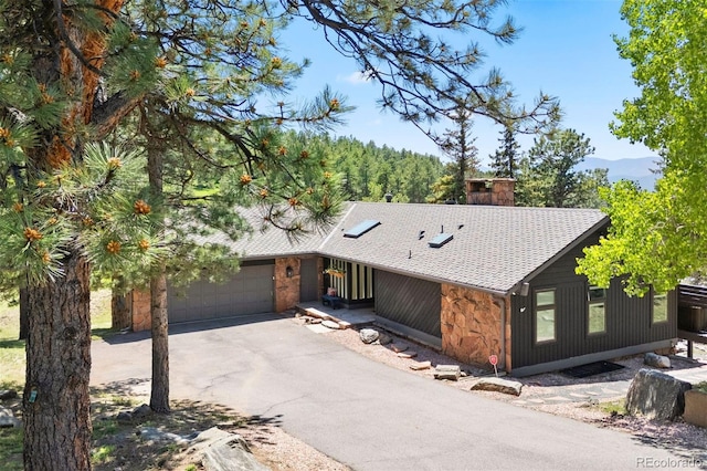1555 Genesee Ridge Rd, Golden, CO 80401 - view of front of house featuring roof with shingles, driveway, an attached garage, and a chimney