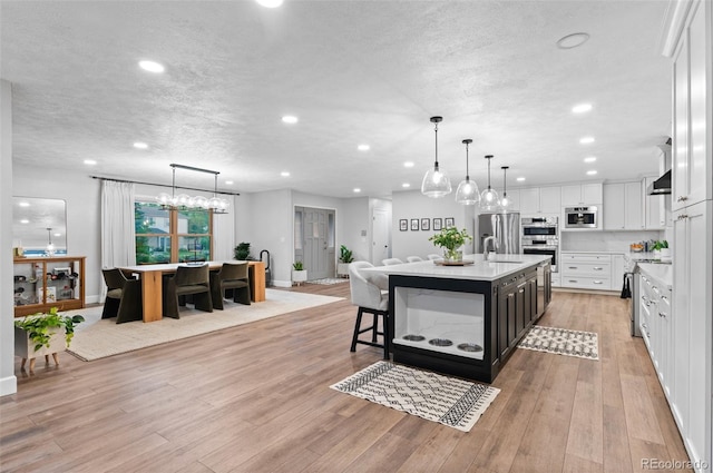 9939 E Aberdeen Ave, Englewood, CO 80111 - kitchen featuring an island with sink, light countertops, stainless steel appliances, a breakfast bar area, and white cabinetry