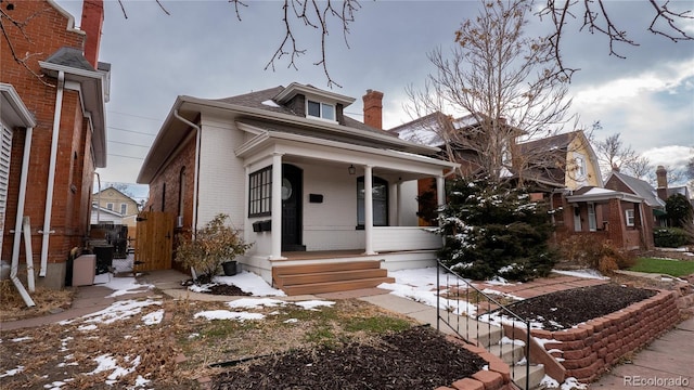 bungalow with covered porch and brick siding