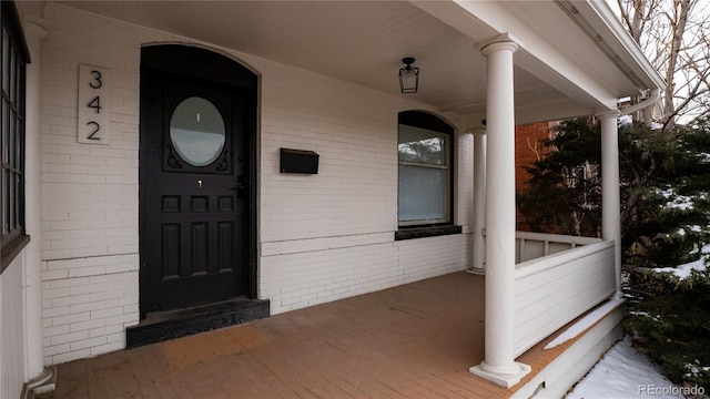 property entrance with a porch and brick siding