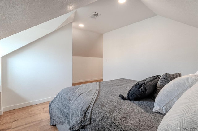 bedroom with lofted ceiling, recessed lighting, visible vents, wood finished floors, and baseboards