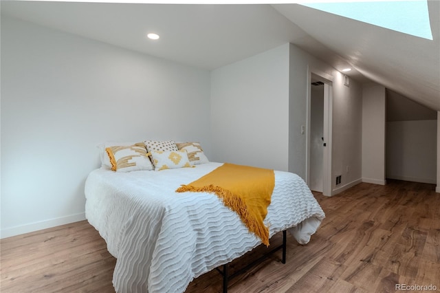 bedroom with recessed lighting, vaulted ceiling, baseboards, and wood finished floors