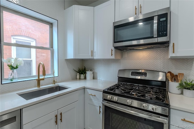 kitchen with a sink, white cabinetry, stainless steel appliances, and light countertops