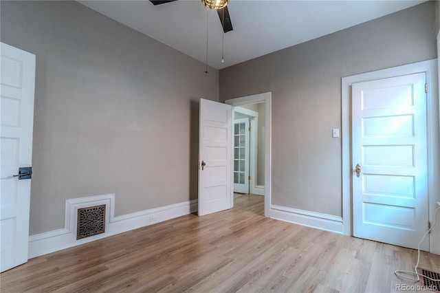 spare room featuring light wood-style floors, visible vents, baseboards, and a ceiling fan