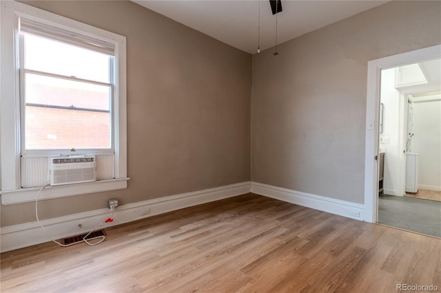 unfurnished room featuring light wood-type flooring, cooling unit, visible vents, and baseboards