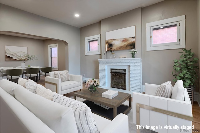 living room featuring arched walkways, a fireplace, wood finished floors, and recessed lighting