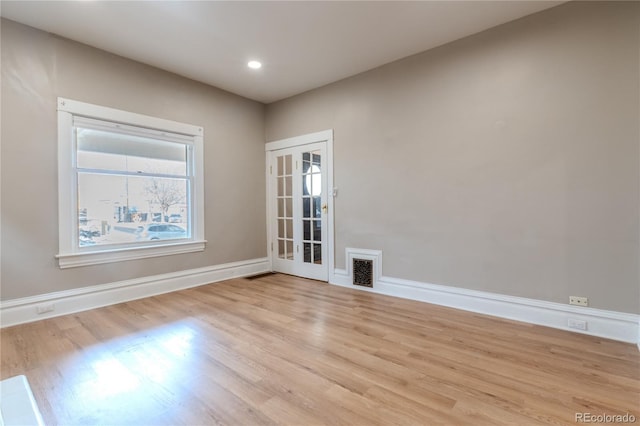 spare room with french doors, light wood finished floors, visible vents, and baseboards