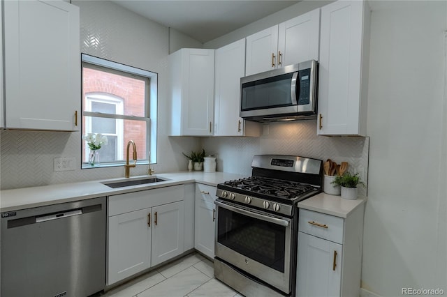 kitchen featuring light countertops, appliances with stainless steel finishes, a sink, and white cabinets