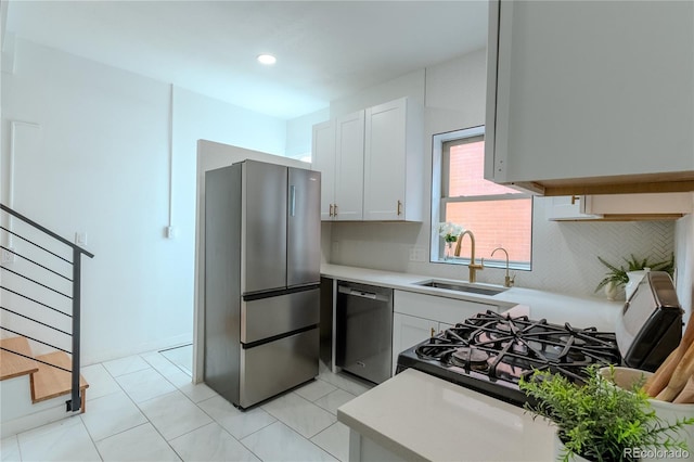 kitchen featuring a sink, white cabinetry, light countertops, appliances with stainless steel finishes, and backsplash