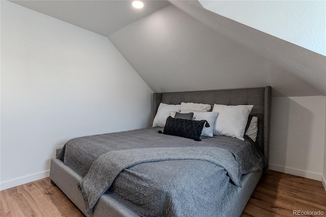 bedroom with lofted ceiling, baseboards, and wood finished floors