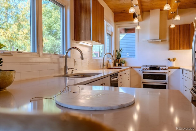 kitchen with pendant lighting, sink, stainless steel range, wall chimney range hood, and white cabinetry