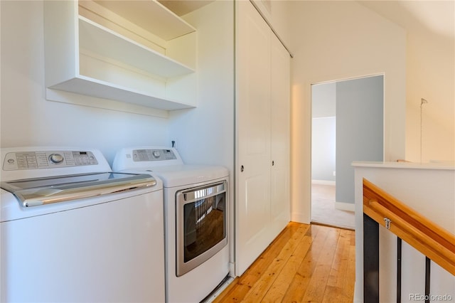 laundry room with light wood-type flooring and washing machine and clothes dryer