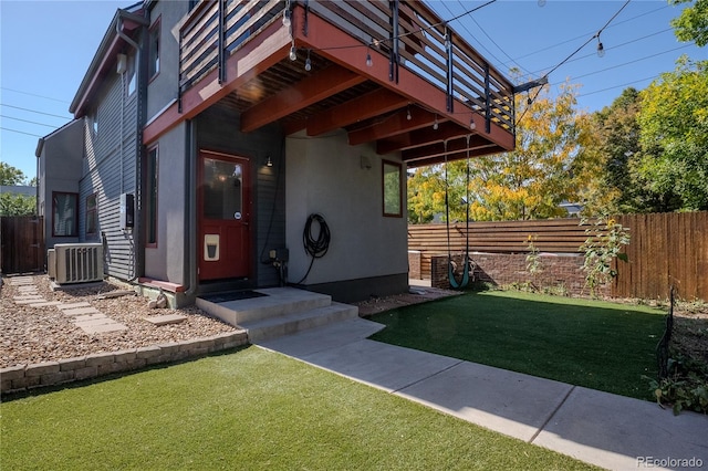 view of exterior entry with central AC unit and a yard