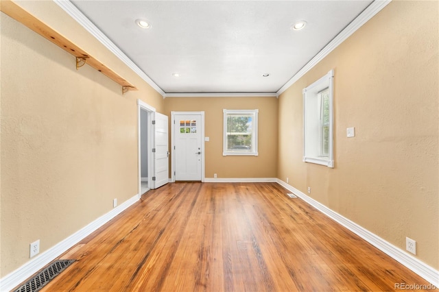 empty room with light hardwood / wood-style floors and ornamental molding