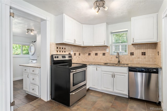 kitchen with stacked washer / drying machine, white cabinetry, sink, and appliances with stainless steel finishes