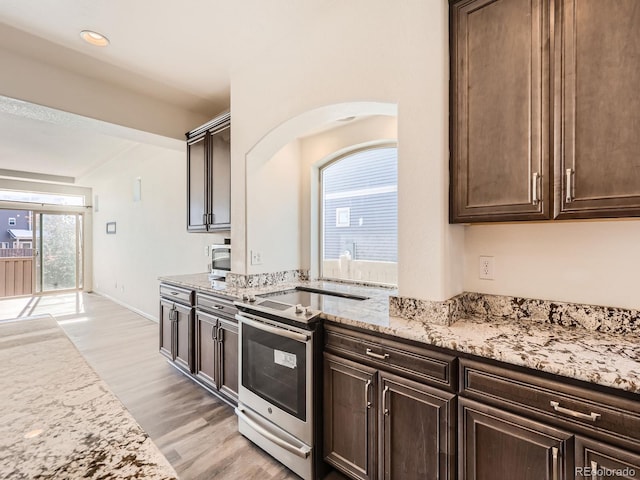 kitchen featuring a healthy amount of sunlight, light stone counters, dark brown cabinetry, and light hardwood / wood-style flooring