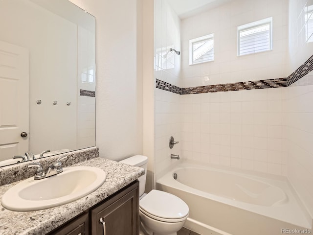 full bathroom featuring vanity, tiled shower / bath combo, and toilet