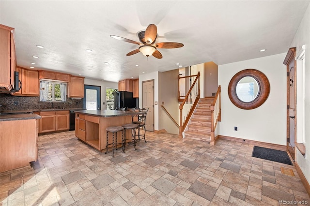 8679 Apache Plume Dr, Parker, CO 80134 - kitchen with black appliances, dark countertops, ceiling fan, a breakfast bar, and tasteful backsplash