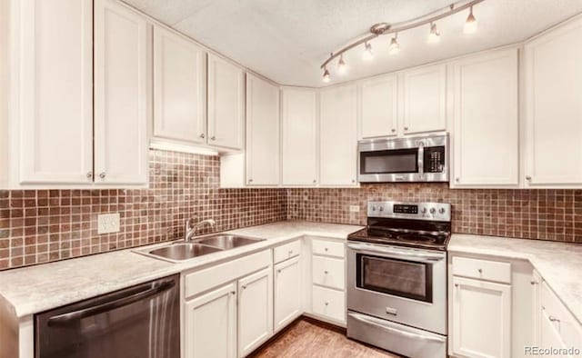 kitchen with appliances with stainless steel finishes, track lighting, sink, light hardwood / wood-style flooring, and white cabinets