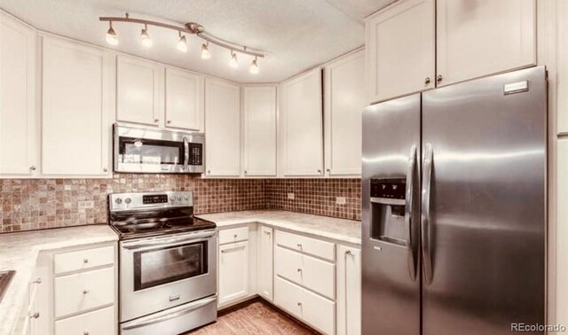 kitchen with white cabinets, tasteful backsplash, light hardwood / wood-style floors, and appliances with stainless steel finishes