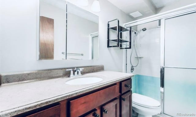 bathroom featuring toilet, a shower with shower door, and vanity with extensive cabinet space