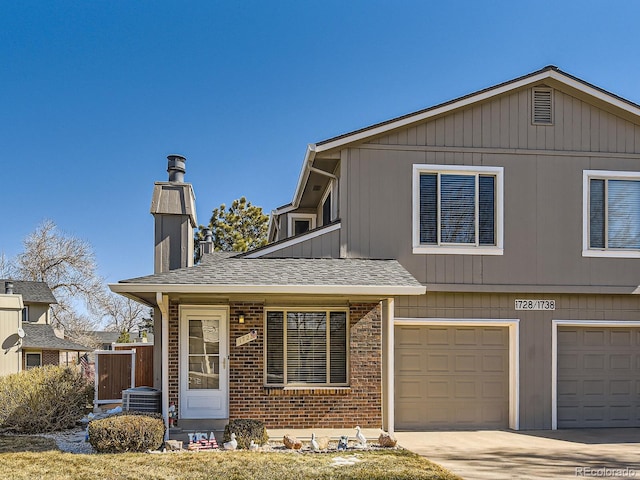 view of front of property featuring brick siding, a shingled roof, an attached garage, central AC unit, and driveway