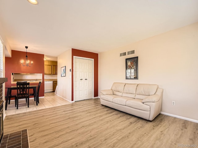 living room with baseboards, a notable chandelier, visible vents, and light wood finished floors