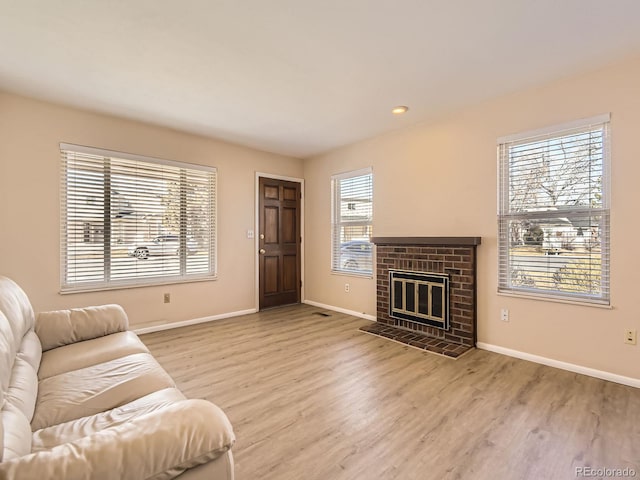 living area featuring recessed lighting, a fireplace, light wood-style flooring, and baseboards