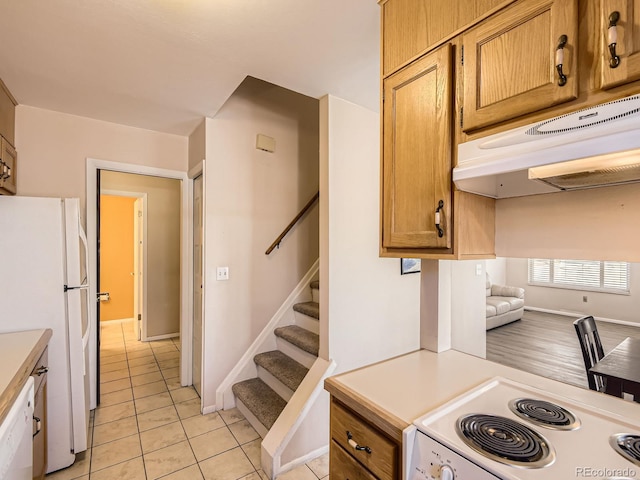 kitchen featuring light tile patterned floors, light countertops, white appliances, and under cabinet range hood