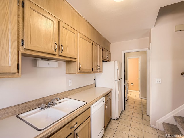 kitchen featuring light brown cabinets, light countertops, white appliances, and a sink