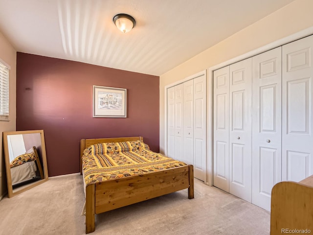 bedroom featuring light carpet and multiple closets