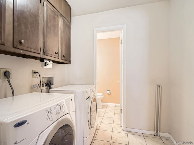 washroom featuring cabinet space, washer and clothes dryer, baseboards, and light tile patterned flooring