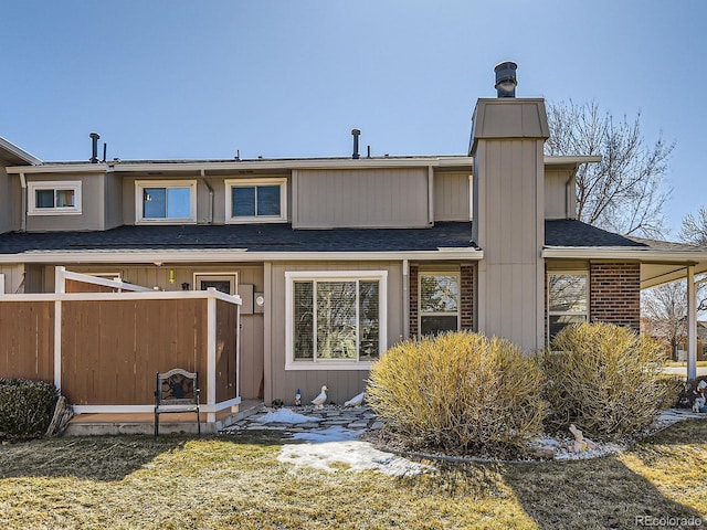 back of property featuring roof with shingles and a lawn