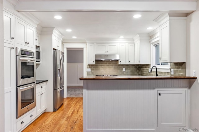 8132 Lodgepole Trl, Lone Tree, CO 80124 - kitchen featuring white cabinets, light wood finished floors, stainless steel appliances, a peninsula, and under cabinet range hood