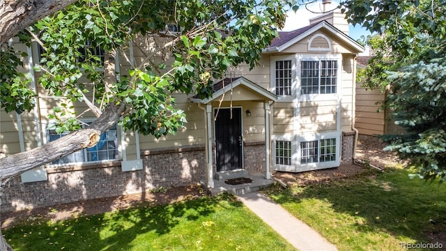 4362 Nepal St, Denver, CO 80249 - view of front of house featuring a chimney, a front yard, and brick siding