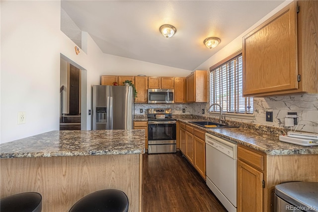 4362 Nepal St, Denver, CO 80249 - kitchen featuring stainless steel appliances, lofted ceiling, tasteful backsplash, dark wood-type flooring, and a kitchen bar