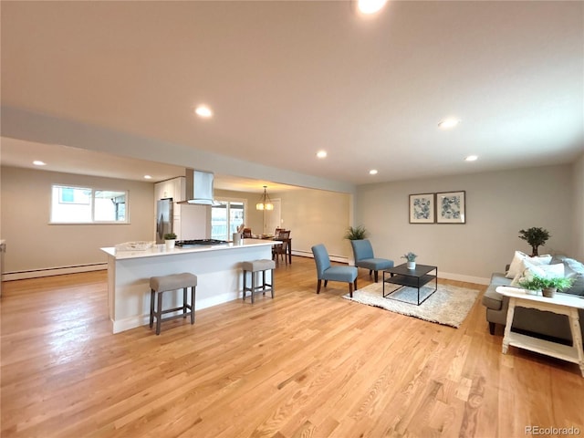 living area with light wood-style floors, a baseboard radiator, baseboards, and recessed lighting