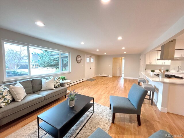 living room featuring a baseboard radiator, light wood-style flooring, recessed lighting, a baseboard heating unit, and baseboards