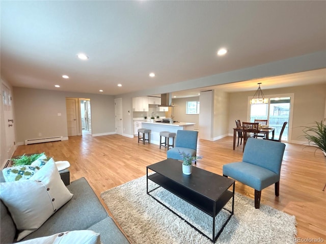 living area featuring a baseboard heating unit, light wood finished floors, and plenty of natural light