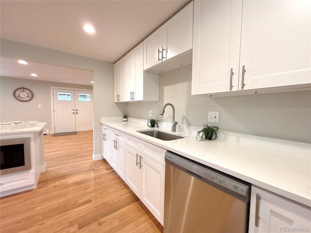 kitchen featuring dishwasher, a sink, light wood-style flooring, and white cabinets