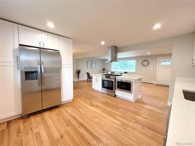 kitchen featuring stainless steel appliances, light countertops, baseboard heating, white cabinets, and island range hood