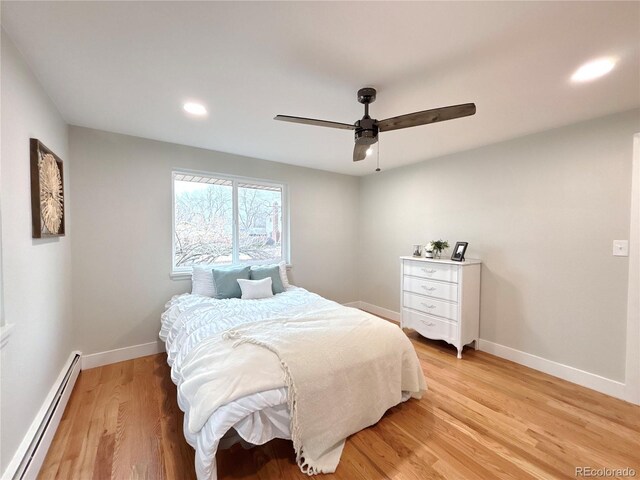 bedroom featuring a baseboard heating unit, light wood-type flooring, baseboards, and a ceiling fan