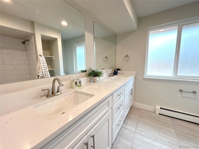 bathroom featuring a baseboard heating unit, a sink, baseboards, and double vanity