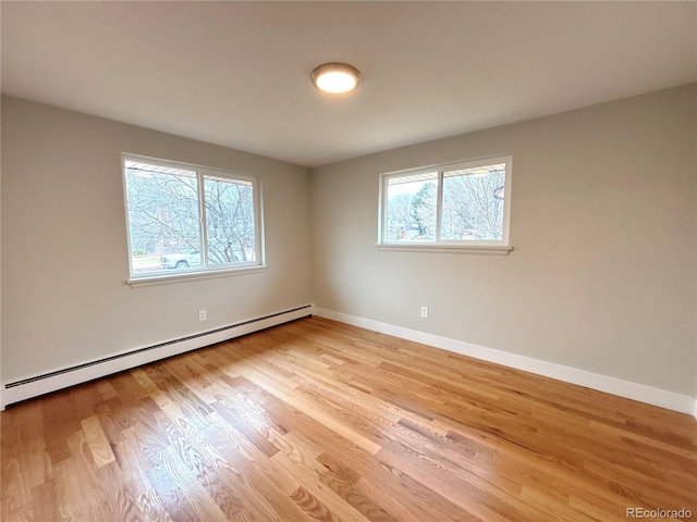 empty room featuring light wood finished floors, plenty of natural light, baseboards, and baseboard heating