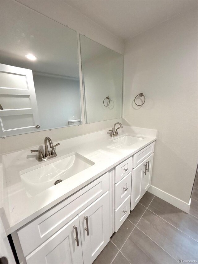 bathroom featuring double vanity, tile patterned flooring, baseboards, and a sink