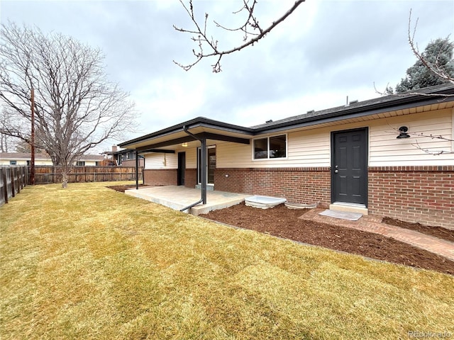 back of property featuring a patio area, fence, a lawn, and brick siding