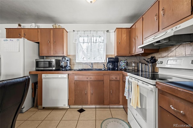 12167 E Exposition Ave, Aurora, CO 80012 - kitchen with white appliances, under cabinet range hood, a sink, decorative backsplash, and brown cabinetry