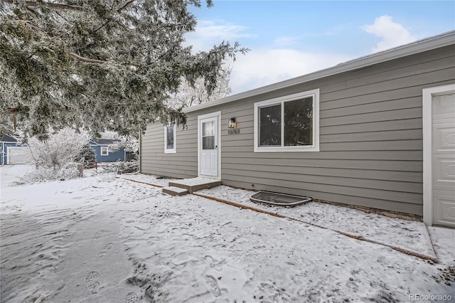 snow covered back of property with a garage