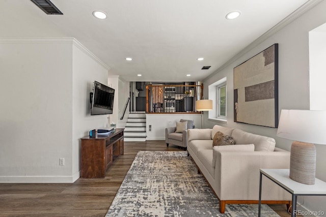 living area with dark wood-type flooring, baseboards, and ornamental molding