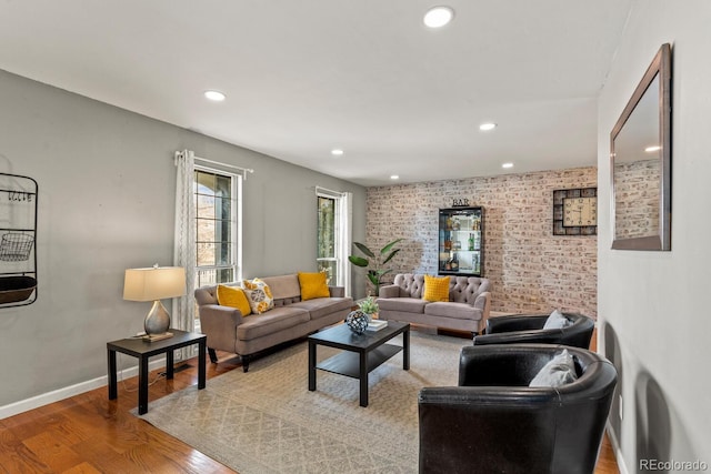 living area featuring recessed lighting, baseboards, wood finished floors, and brick wall